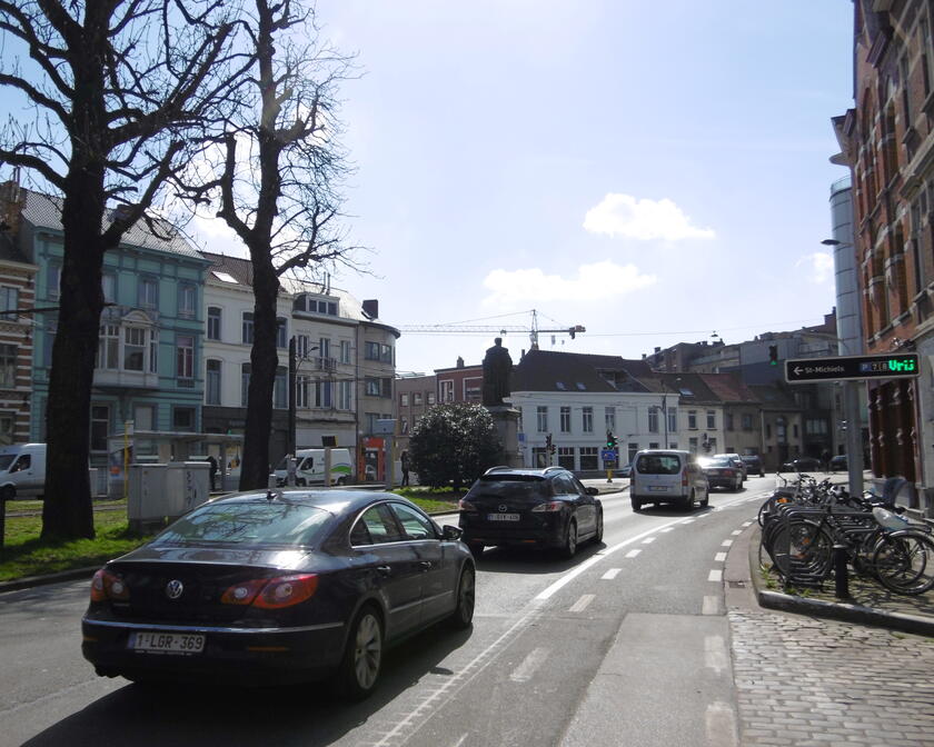 Cars are driving on the main road going round the city of Ghent. You can see a sign pointing to the direction of 'Sint-Michielsparking'.