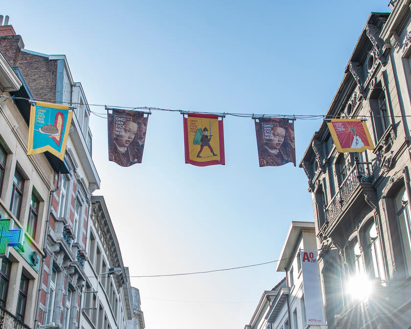 vlaggetjes met reclame van Van Eyck die tussen gebouwen hangen