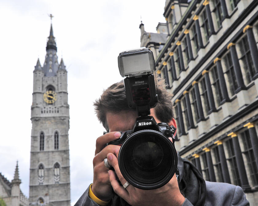 De fotograaf gefotografeerd aan de gevel van het Stadhuis, met het Belfort als achtergrond