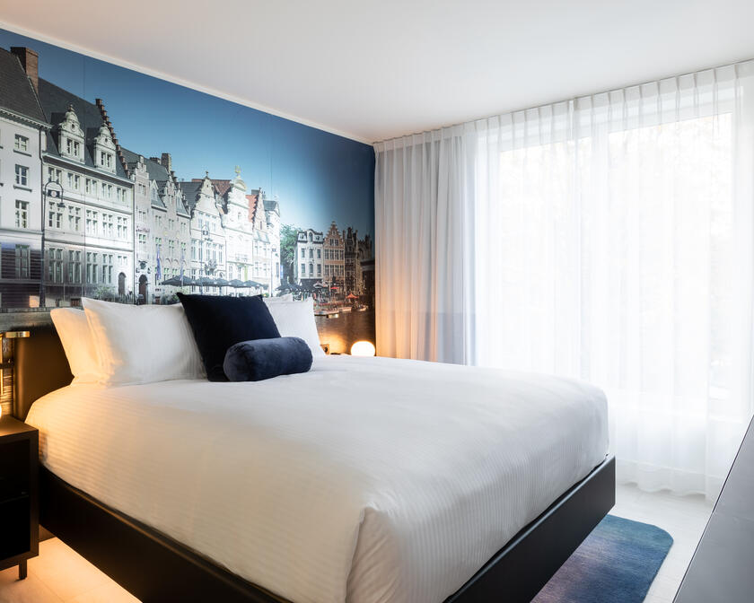 hotelkamer met tweeprsoonsbed, tv en op de muur een foto van gebouwen in Gent