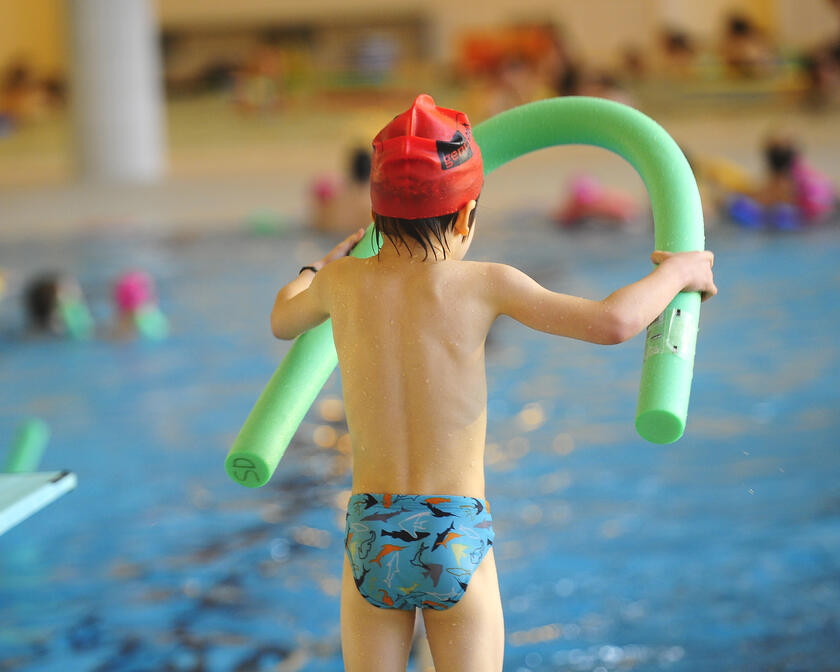 Close-up van kind aan de rand van het zwembad, klaar om te springen.