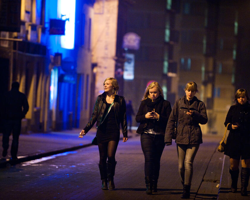 Vier jonge meisjes in winterse kledij die 's nachts over straat wandelen.