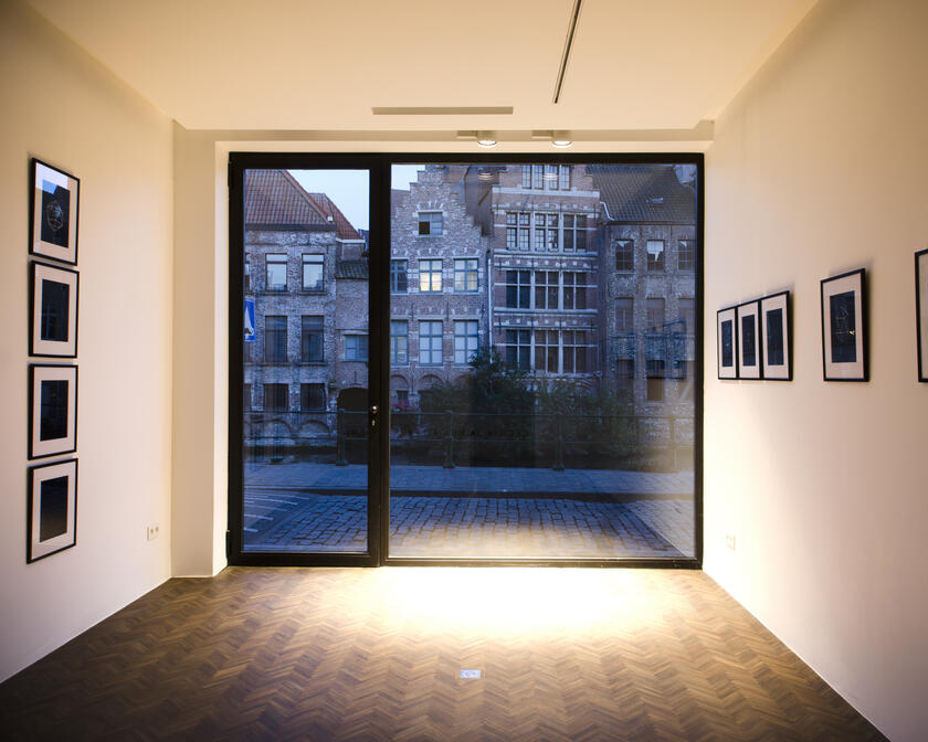 kamer met foto's aan de muren, ramen die uitkijken op de straat