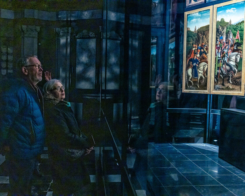 Two people admire the Ghent Altarpiece at its new location in St Bavo Cathedral