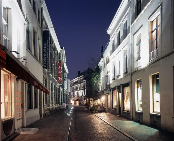 Narrow shopping street with illuminated shop windows at dusk