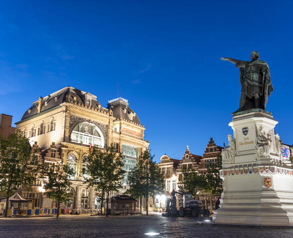 Illuminated facade of Bond Moyson and illuminated statue of Jacob Van Artevelde in the middle of the Vrijdagmarkt in Ghent