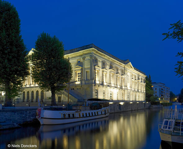 Antiguo Palacio de Justicia iluminado con reflejo en el agua en Gante