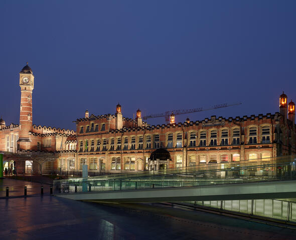 Die beleuchtete Fassade und der Turm des Bahnhofs Gent-Saint-Pierre bei Nacht