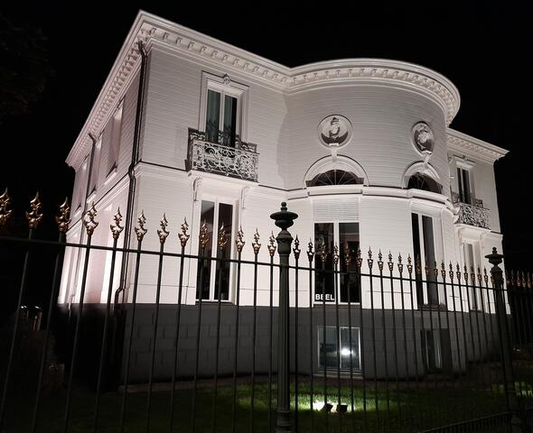Beleuchtete weiße Fassade der Villa mit halbkreisförmigem Anbau im Lousberg-Park in Gent