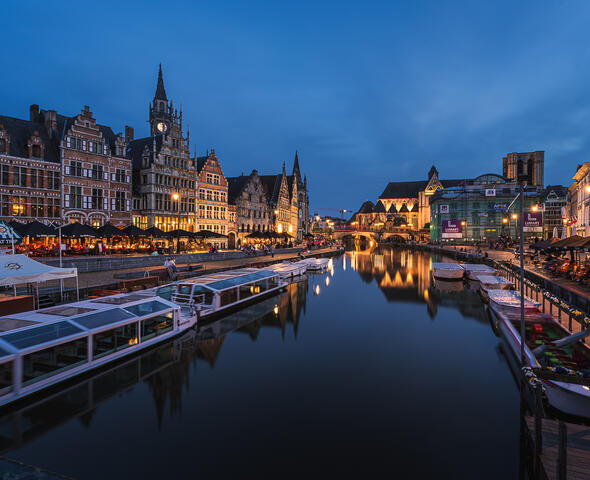 De verlichte middeleeuwse haven van Gent bij valavond