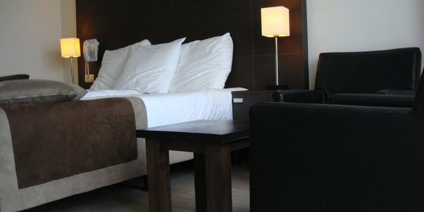 Deze hotelkamer heeft donkerbruine houten accenten en er staat een zwarte lederen zetel in de kamer.