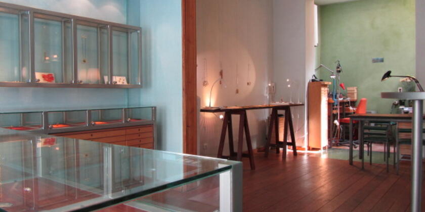 Tentoonstellingsruimte met verschillende objecten achter glas, de donkere houten vloer valt op.