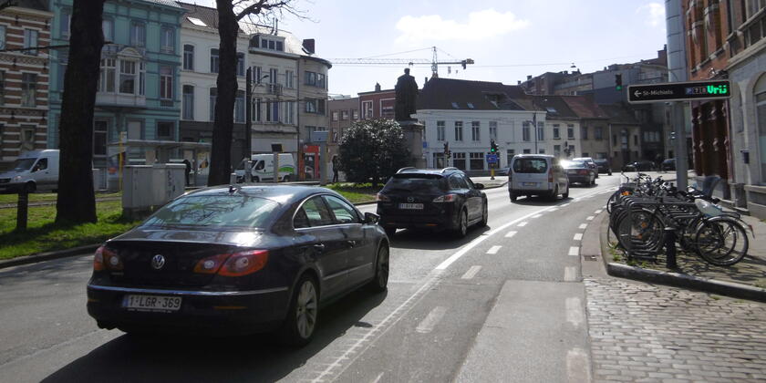 Cars are driving on the main road going round the city of Ghent. You can see a sign pointing to the direction of 'Sint-Michielsparking'.