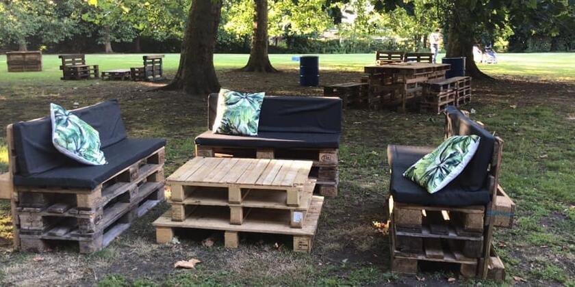banken en tafels gemaakt van houten paletten, zwarte kussens op de banken, kleine kussens met planten op