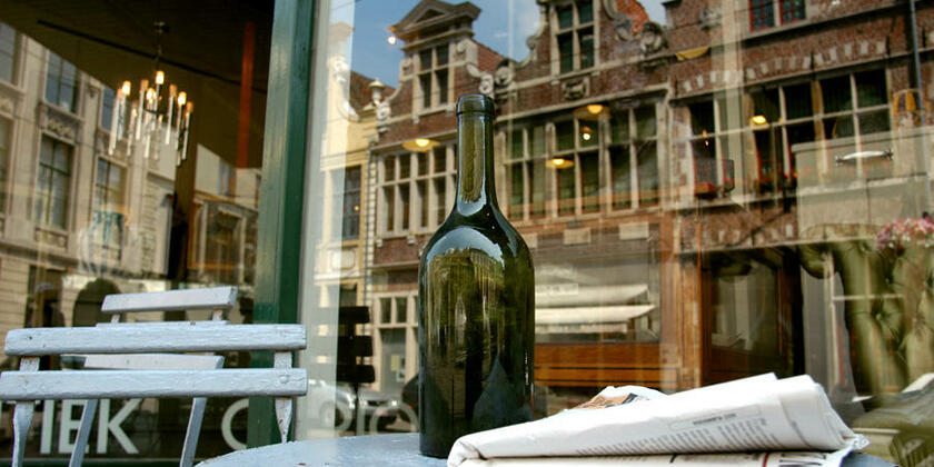 Fles wijn op een tafeltje voor B&B Baeten. In de reflectie van het raam zien we de mooie rijhuizen aan de overkant