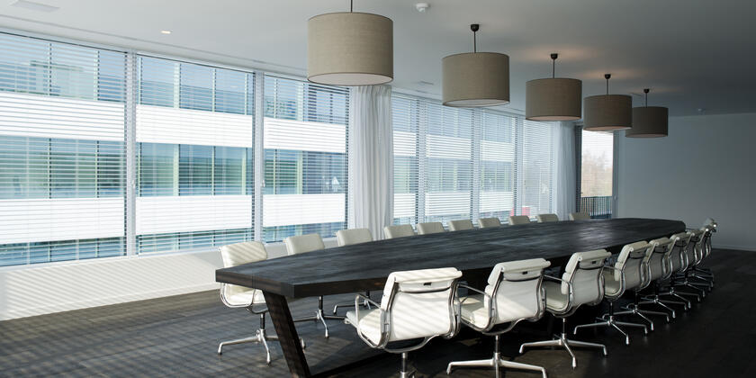 Zeer modern ingerichte vergaderzaal met lange tafel en witte stoelen