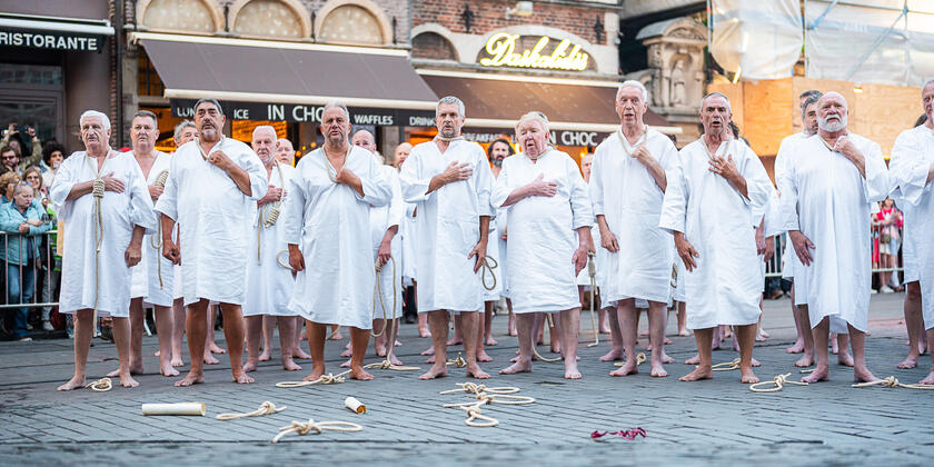 Des hommes en robe blanche avec une écharpe autour de leur cou pendant le stroppenstoet des festivités de Gand