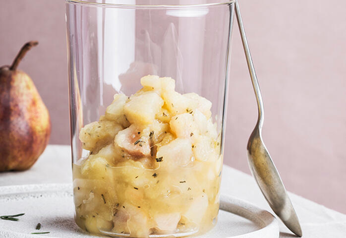 appel- en perenmoes met saffraan in een glas waartegen een lepel staat