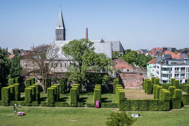 romaanse abdijkerk met daarvoor verschillende hagen en een grasveld