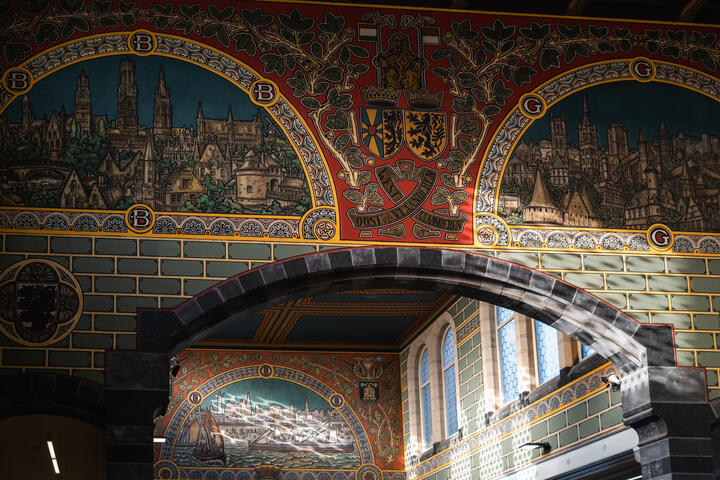 Foto van enkele muurschilderingen in het station Gent-Sint-Pieters. De foto toont de muurschilderingen van Brugge, Gent en Oostende.