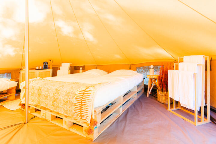 Espace de couchage à l'intérieur d'une tente glamping sur camping Urban Garden Blaarmeersen