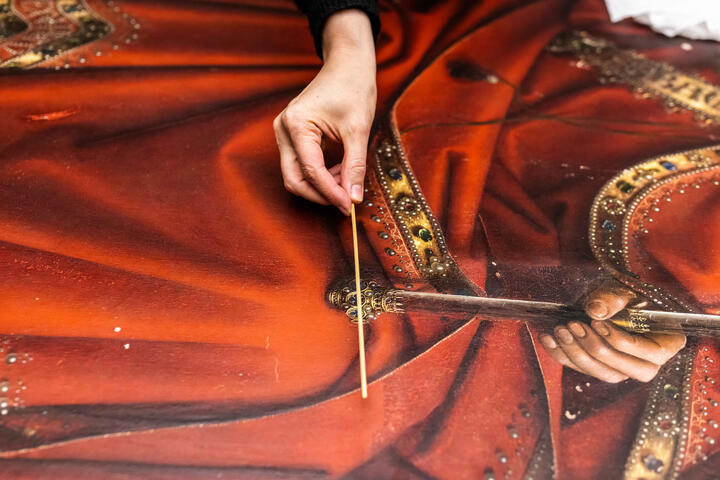 Der Restaurator des Genter Altars zeigt mit einem Stock auf die Details des Gemäldes