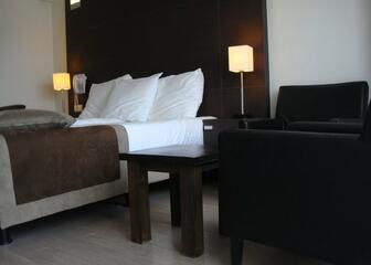 Deze hotelkamer heeft donkerbruine houten accenten en er staat een zwarte lederen zetel in de kamer.