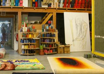 Kunstenares in kunstatelier met gekleurde naaigaren en schilderdoeken.
