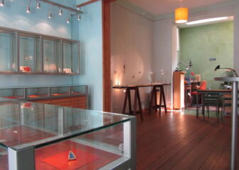 Tentoonstellingsruimte met verschillende objecten achter glas, de donkere houten vloer valt op.