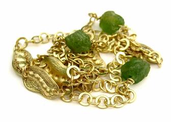 Detail van een gouden ketting van aaneengeschakelde ringetjes, met kleine groene smaragden.