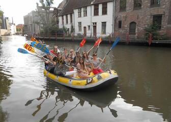 Enthousiaste groep dames in rubberboot zwaaien met hun peddels.