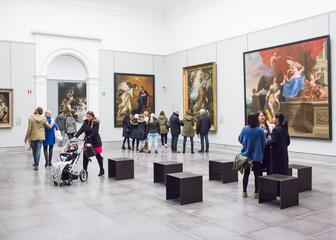 Vista interior de visitantes en una sala del museo de bellas artes. En las paredes hay cuadros de la época barroca
