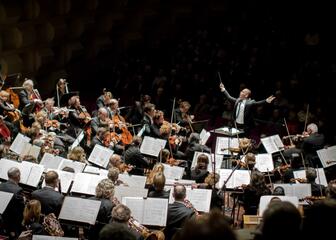 Dirigent leidt een groot symfonieorkest op het Festival van Vlaanderen