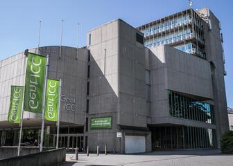 Gent ICC, grijs gebouw met ervoor 3 groene vlaggen met Gent ICC erop