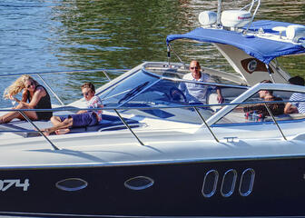 5 summerly dressed people enjoying a boat trip in a small yacht