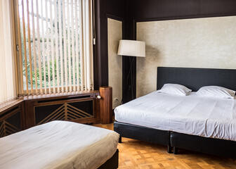 Sobere familieslaapkamer met beige muren en zwart plafond en bedframe.
