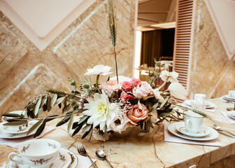 een gedekte tafel met een roze en wit bloemstuk 