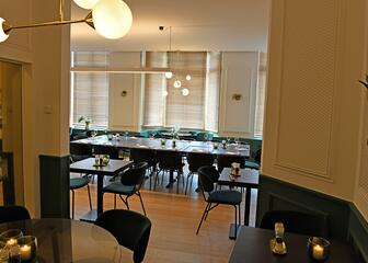 Eerste verdieping met zwarte tafels, crème muren, ingericht voor groepen.