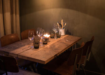 Rechthoekige tafel voor vier, gedekt met water- en wijnglazen.