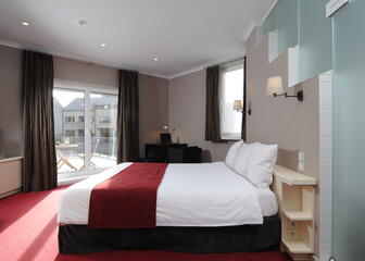 Tweepersoonskamer met klein terras badend in de zon in hotel Astoria Gent. 