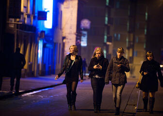 Vier jonge meisjes in winterse kledij die 's nachts over straat wandelen.