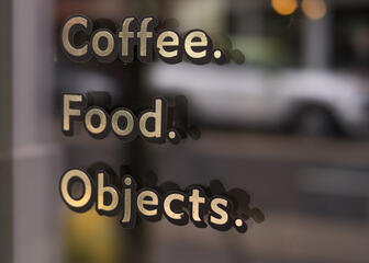 Close-up van het opschrift op het raam: Coffee, Food en Objects.