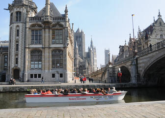 Toeristenbootje aan de Sint-Michielsbrug met op de achtergrond de drie torens van Gent.