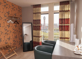 Hotelkamer met rode en oranje accenten met zicht op het station van Gent-Sint-Pieters.