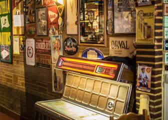 Jukebox tegen een muur met reclameborden voor trappist bieren.