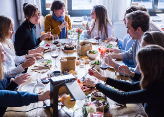 mensen aan tafel die eten van tapas, raclette, brood, … met drankjes