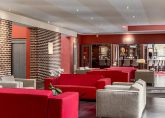 Lobby met rode en grijze stoffen zetels.