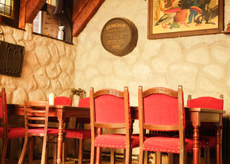 Binnenzaal met houten tafels en roodleren stoelen.