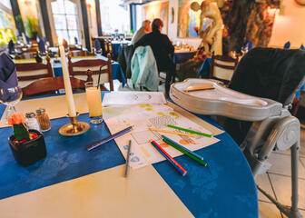 Interieur van Grieks restaurant. Focus op lege kinderstoel en tekening met kleurpotloden op de tafel.