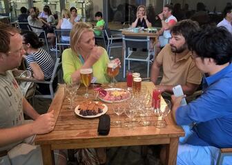 Vier mensen drinken bier en eten hapjes op een terras.